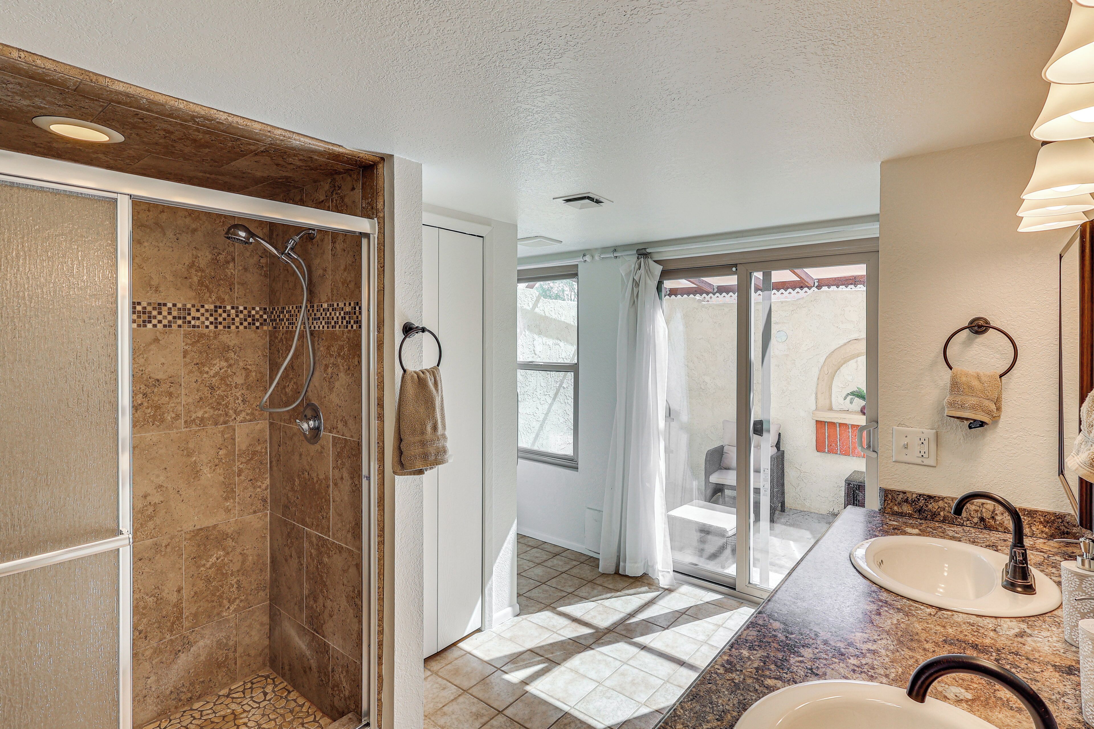 Une salle de bain avec douche, lavabo et vue sur un balcon.