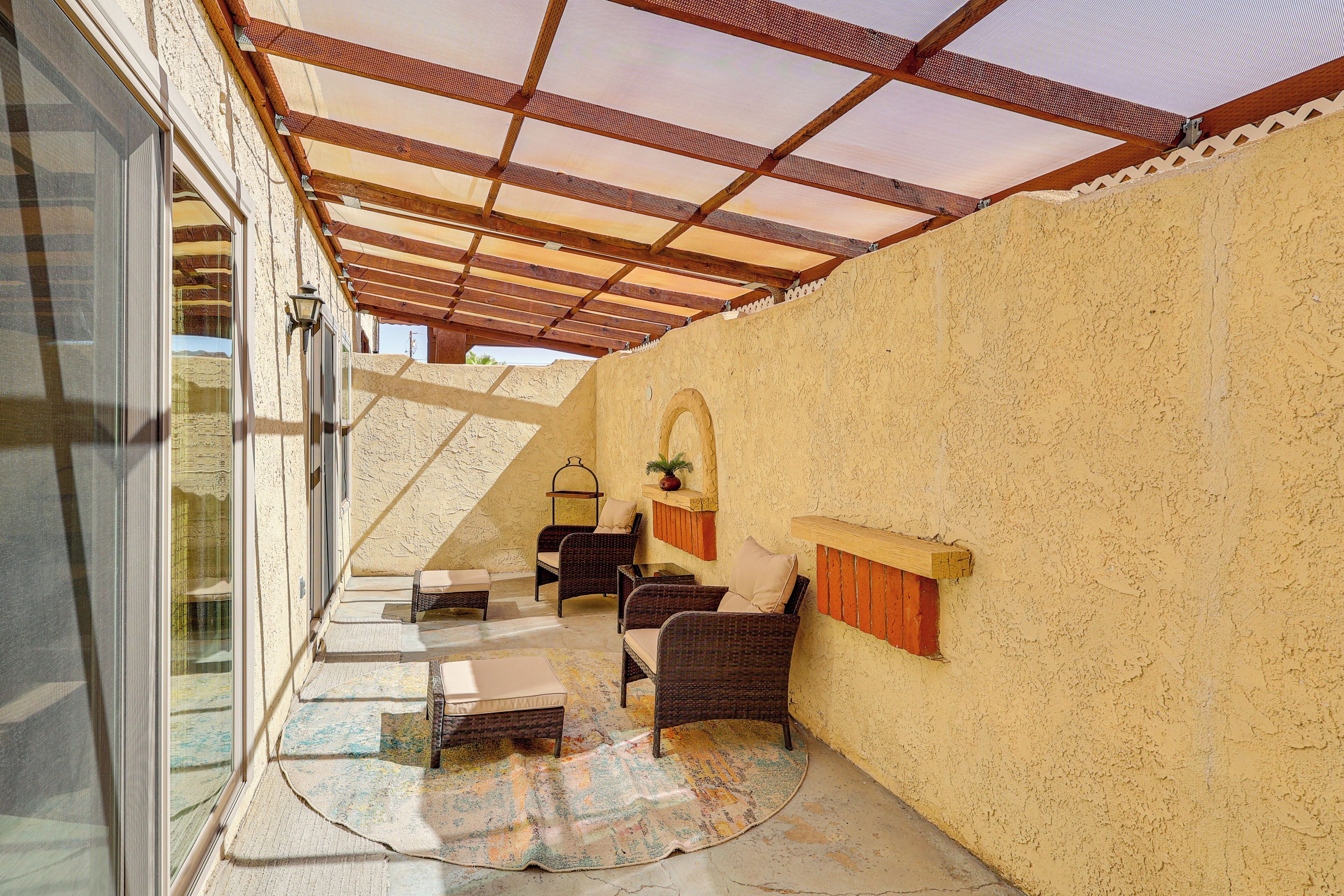 A covered outdoor seating area with wicker furniture and a view of the interior.