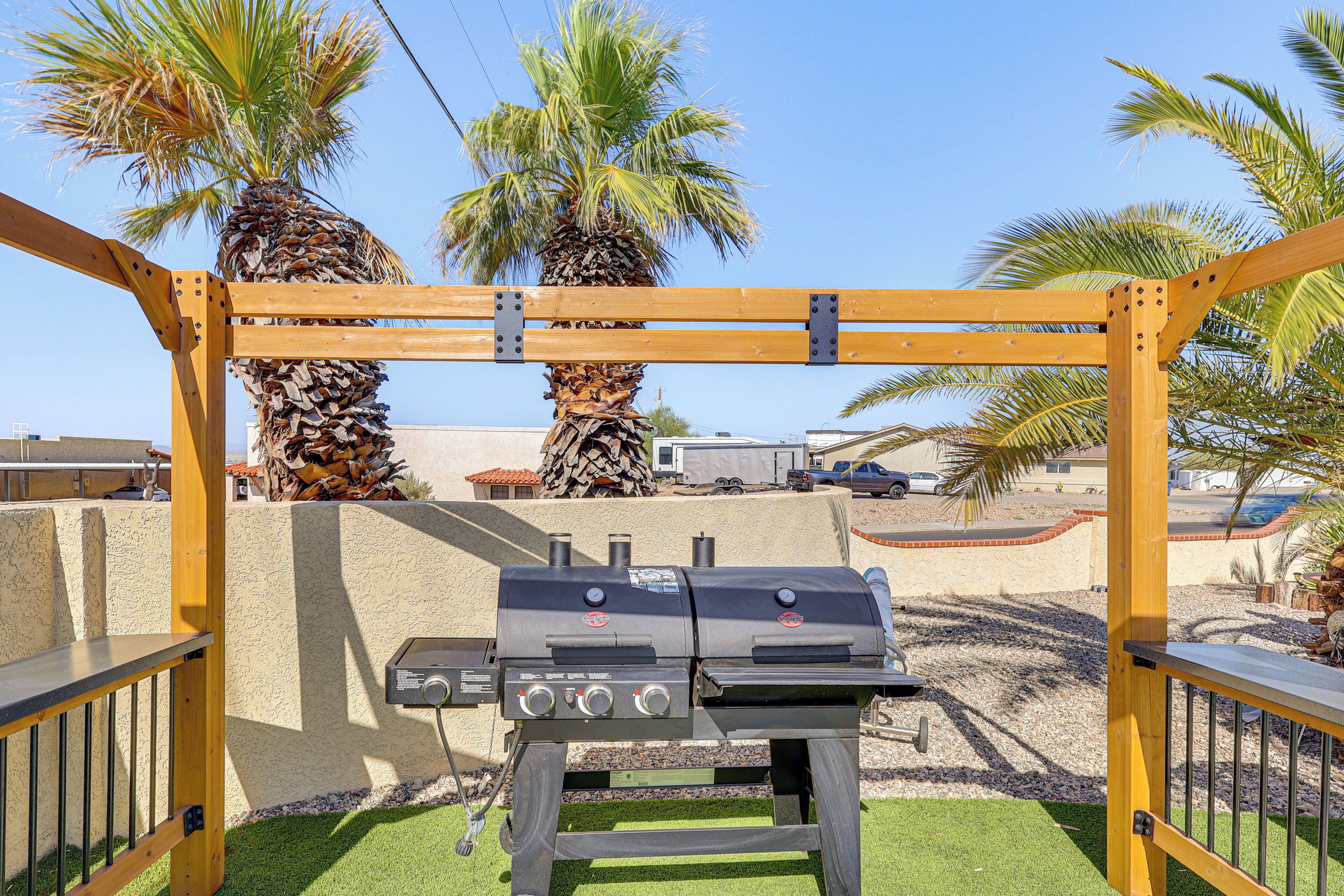 Un barbecue doté d’un panneau de commande, placé sur un fond de palmiers et d’un ciel dégagé.