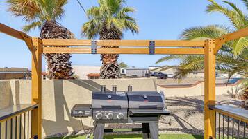 Un barbecue doté d’un panneau de commande, placé sur un fond de palmiers et d’un ciel dégagé.