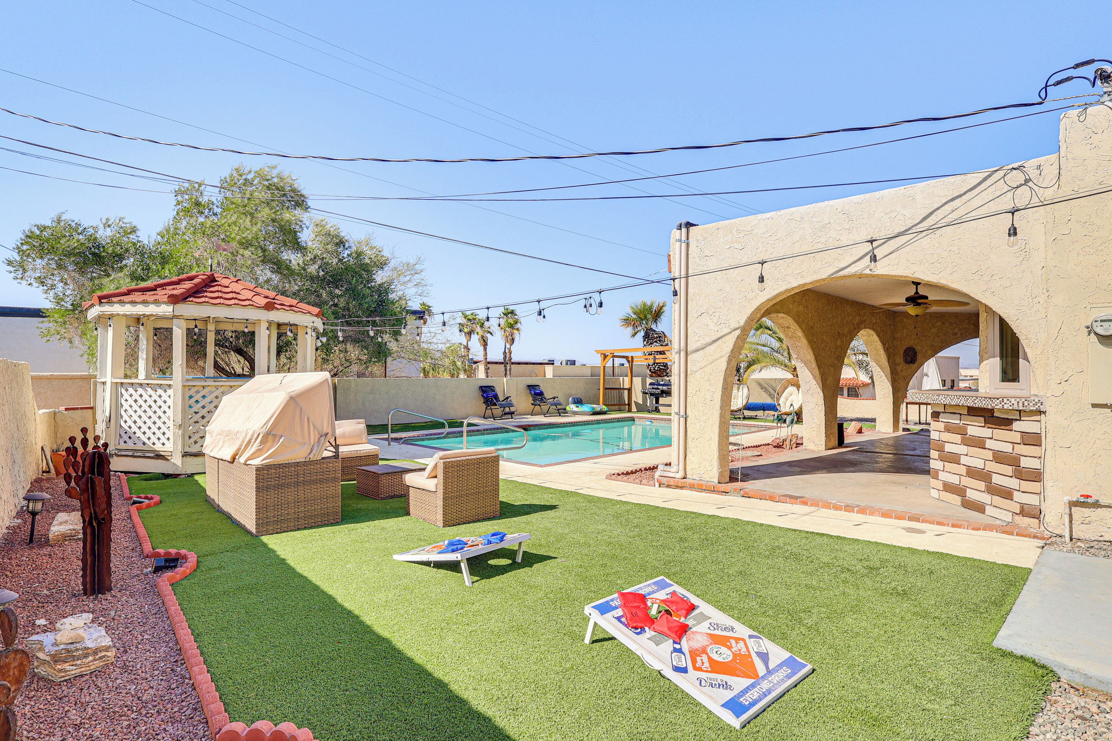 A backyard with a swimming pool, outdoor seating, and a gazebo.