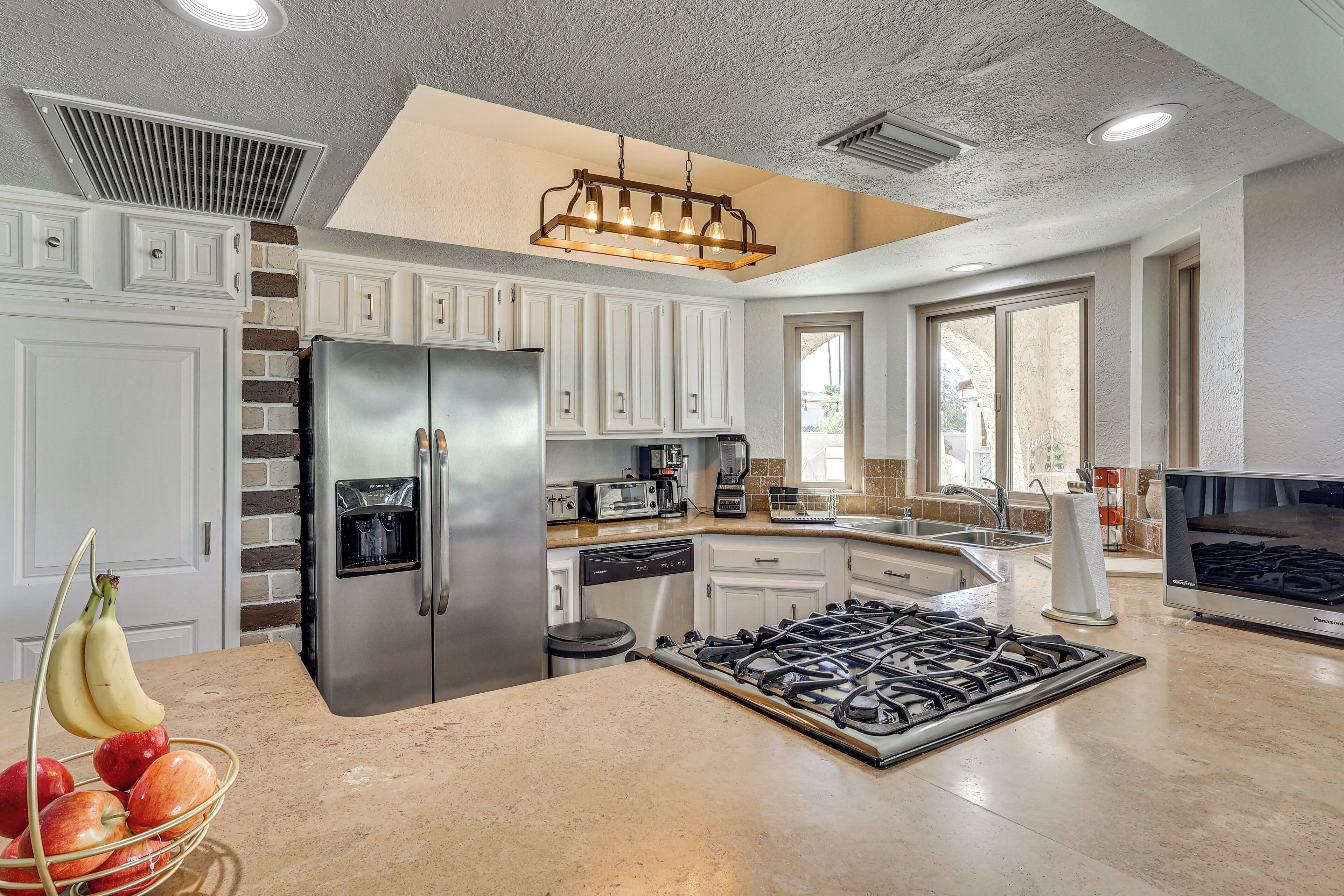 A kitchen with white cabinets, a stainless steel refrigerator, a gas stove, and a water dispenser.