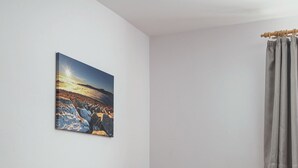 A small, cozy room with a wooden bench, a single sofa with a patterned pillow, and a painting of a landscape on the wall. - Pension U Komárků (Špindlerův Mlýn)