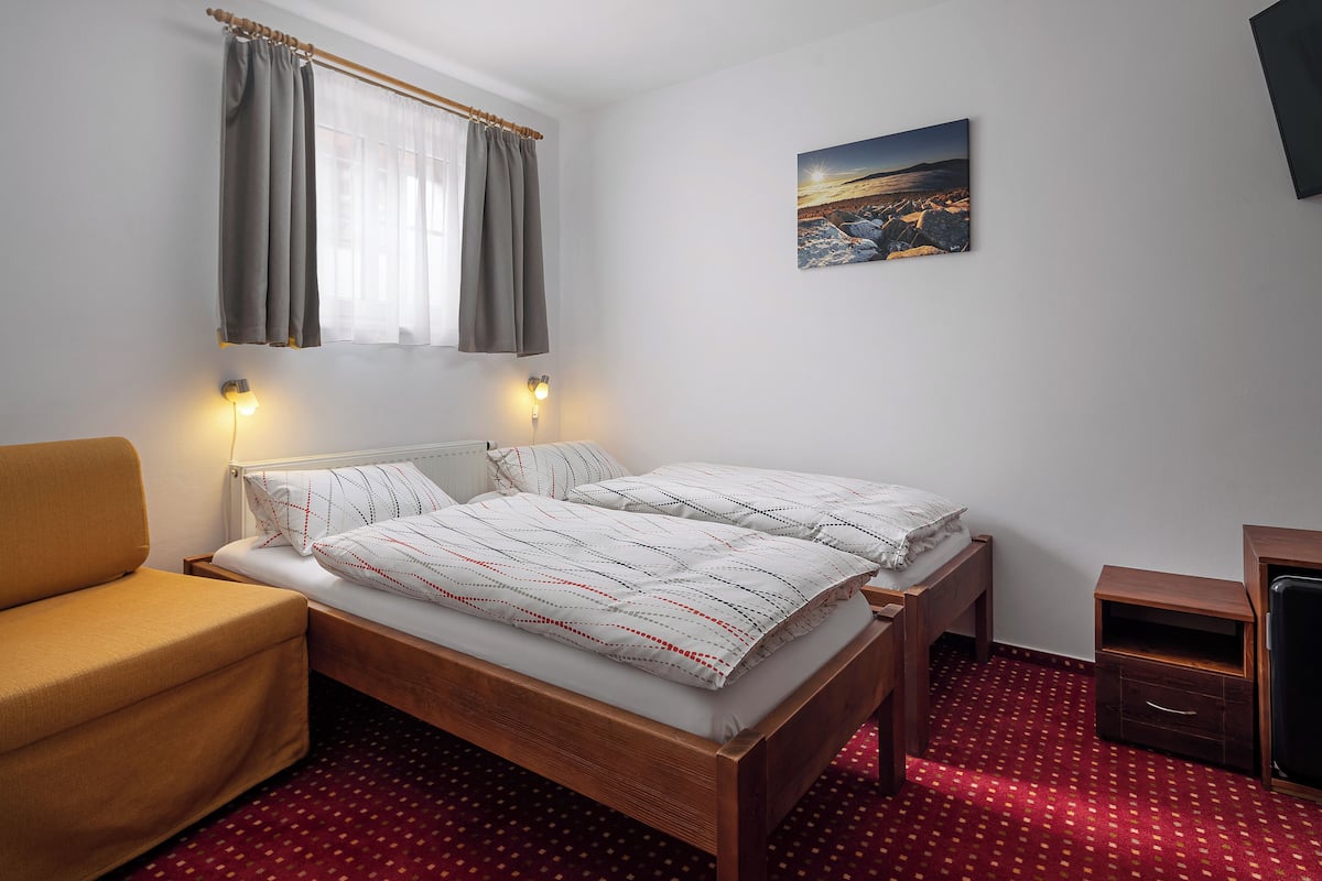 Ein Schlafzimmer mit einem hölzernen Bett, einer Couch, einem Nachttisch und einem an der Wand befestigten Fernseher.