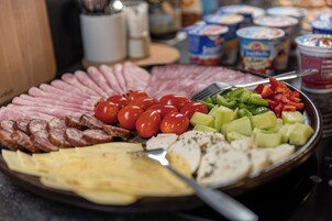 Una bandeja con carnes, quesos y verduras variados.