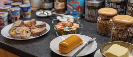 A kitchen counter with various food items and condiments, including jars of coffee, a glass dish with a cake, and plates with food.