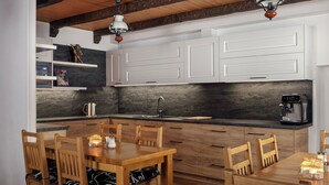 A modern kitchen with white cabinets, a wooden dining table, and two pendant lights. - Pension U Komárků (Špindlerův Mlýn)