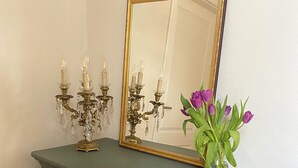 Un aparador verde con candelabros de latón y un espejo.