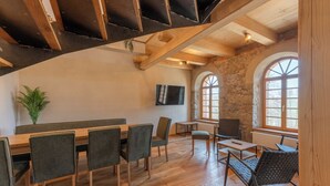 Un comedor con mesas y sillas de madera, paredes de piedra y un amplio ventanal de arco.