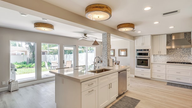A spacious kitchen with a large island, white cabinetry, and a view to the backyard. - Spacious Yard, Near Golf: Modern Home in Hollywood (Hollywood)