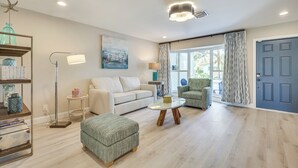 A living room with a white sofa, a green armchair, a round coffee table, and a bookshelf. - Spacious Yard, Near Golf: Modern Home in Hollywood (Hollywood)