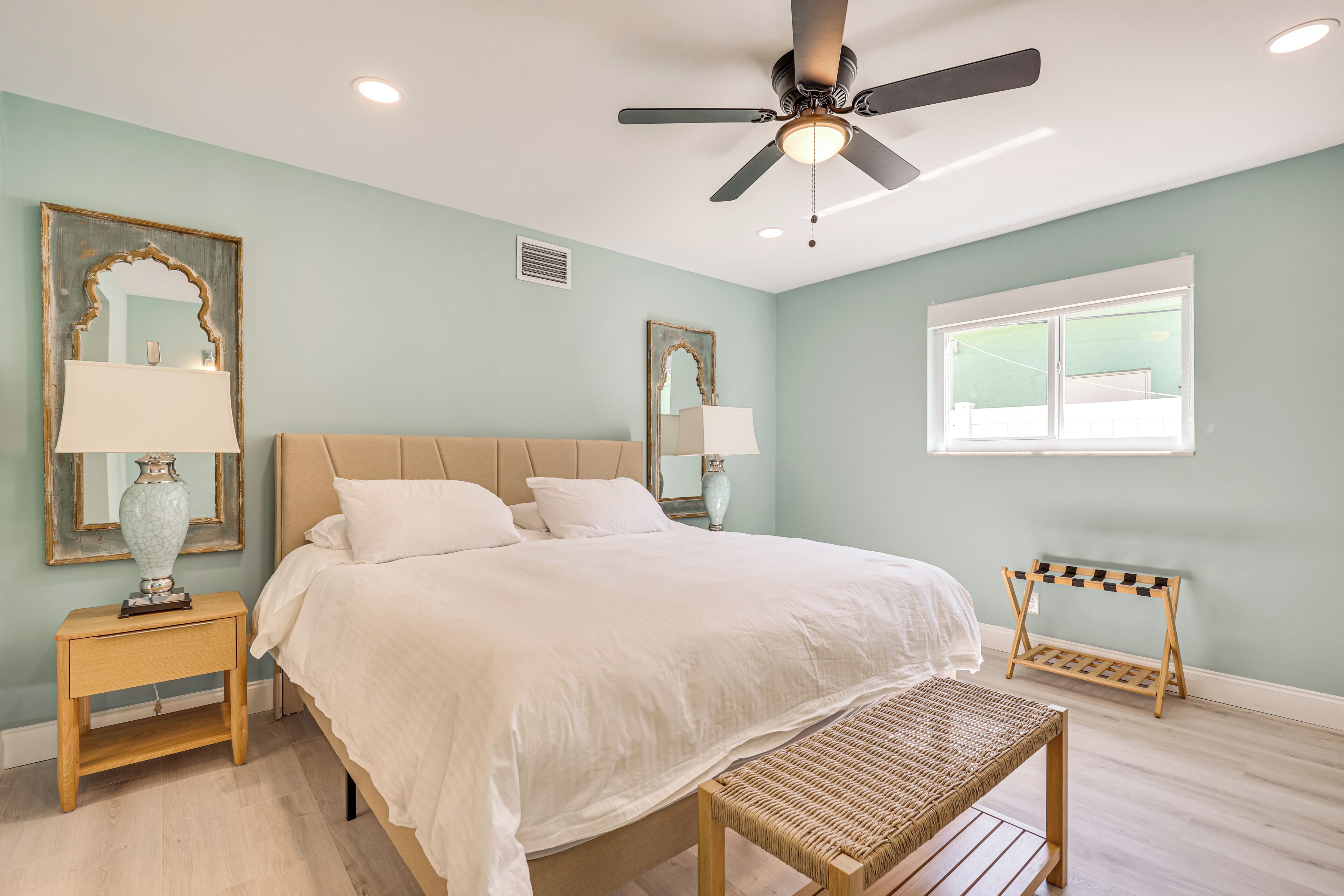 A bedroom with a bed, nightstands, a ceiling fan, and a window.
