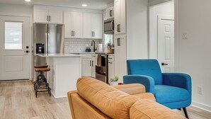 A modern kitchen with white cabinets, stainless steel appliances, and a blue chair. - Near Historic Georgetown Square! Updated Home (Georgetown)