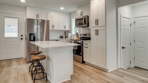 A modern kitchen with white cabinetry, stainless steel appliances, and a central island with stools. - Near Historic Georgetown Square! Updated Home (Georgetown)