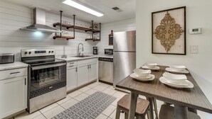 A modern kitchen with stainless steel appliances, wooden shelves, and a dining table set with white plates. - 2 Mi to Dollywood! Golfview Resort Condo w/ Pools (Pigeon Forge)