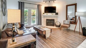 A living room with a fireplace, a sofa, a coffee table, and a TV. - 2 Mi to Dollywood! Golfview Resort Condo w/ Pools (Pigeon Forge)