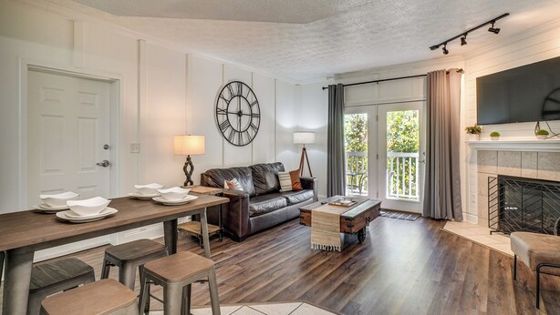 A modern living room with a fireplace, a large clock, and a dining area with stools. - 2 Mi to Dollywood! Golfview Resort Condo w/ Pools (Pigeon Forge)