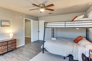 A bunk bed with a ceiling fan, a bedside table with a lamp, and a door leading to another room. - 3 Mi to Texas Tech: Cozy Home w/ Private Yard! (Lubbock)