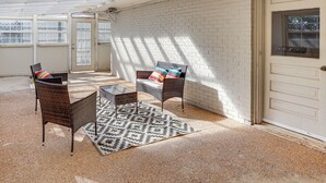 An outdoor patio with wicker furniture, a patterned rug, and a white brick wall. - 3 Mi to Texas Tech: Cozy Home w/ Private Yard! (Lubbock)