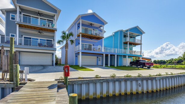A waterfront property with multiple levels, a dock, and a red truck parked nearby. - Fish, Swim & Explore: Panama City Gem w/ Boat Slip (Panama City)
