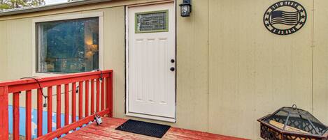 A wooden deck with a red railing, a white door, and a small outdoor lamp.
