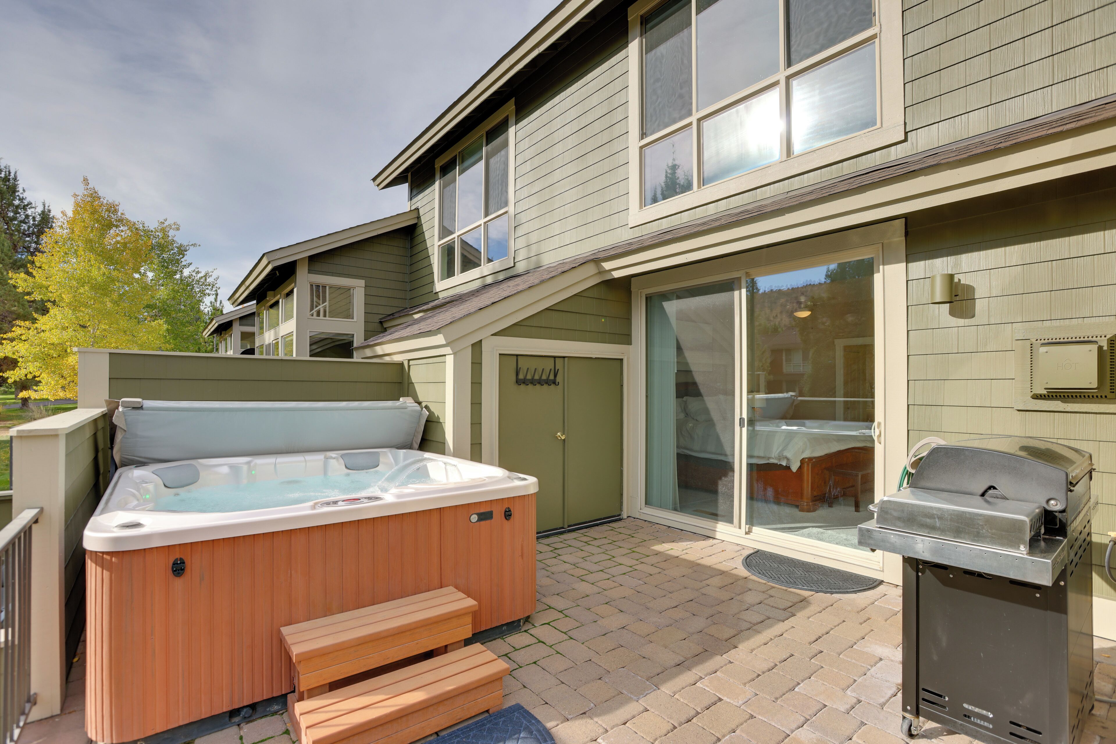 A backyard with a hot tub, a grill, and a covered patio area.