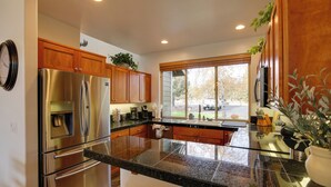 A modern kitchen with stainless steel appliances, wooden cabinets, and a large island with a sink.