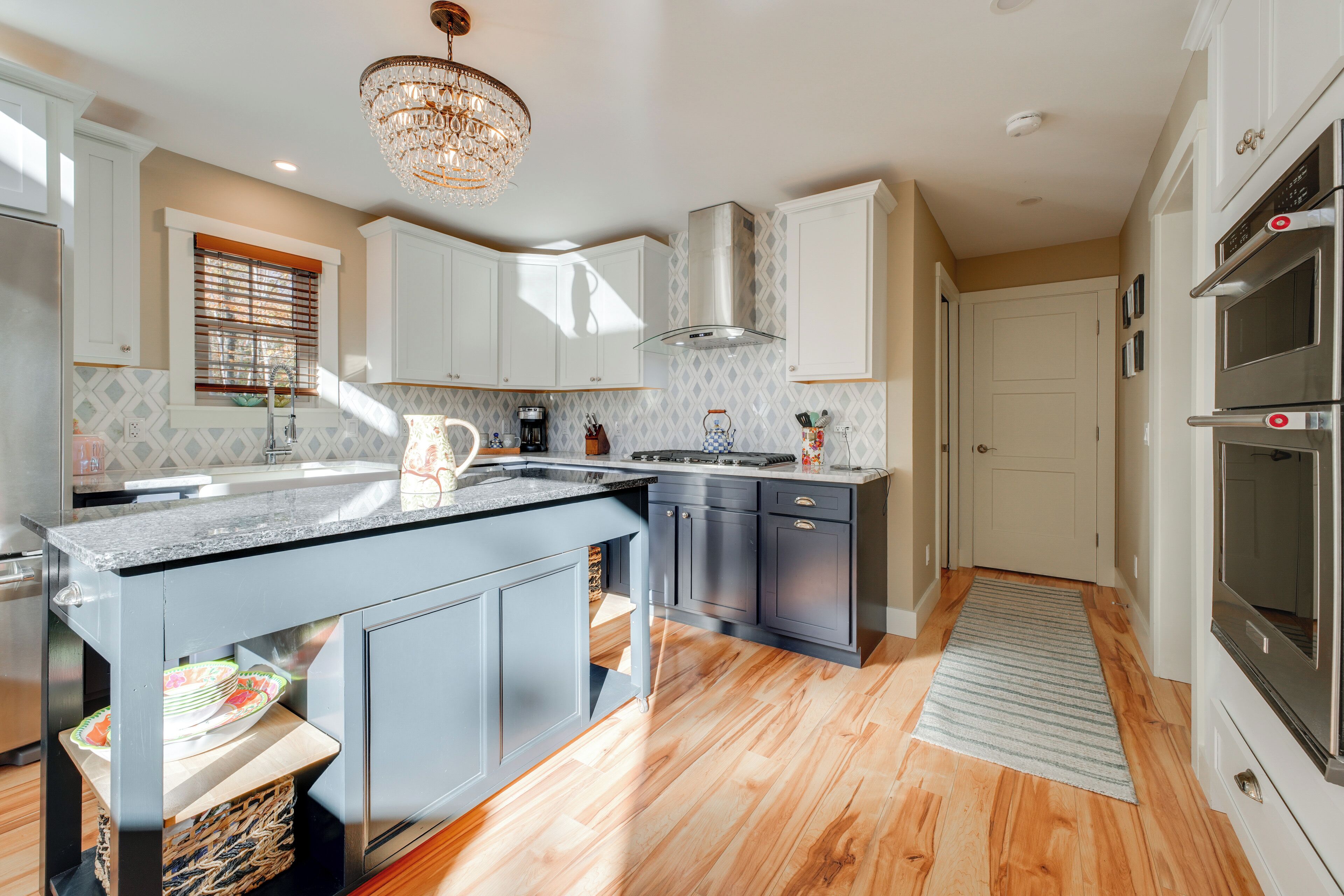 A modern kitchen with a central island, built-in appliances, and a chandelier.