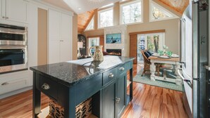 A modern kitchen with a central island, built-in appliances, and a fireplace. - 'valhalla': Family Home on Frye Island w/ Golf! (Raymond)