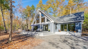 A modern house with a large porch, surrounded by trees and a gravel driveway. - 'valhalla': Family Home on Frye Island w/ Golf! (Raymond)