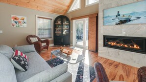 A spacious living room with a fireplace, wooden ceiling, and large windows. - 'valhalla': Family Home on Frye Island w/ Golf! (Raymond)