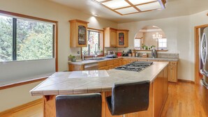 A spacious kitchen with a large island, wooden cabinets, and a view of the outdoors. - 3 Mi to Sequoia Park Zoo: Spacious Home w/ Sunroom (Eureka)