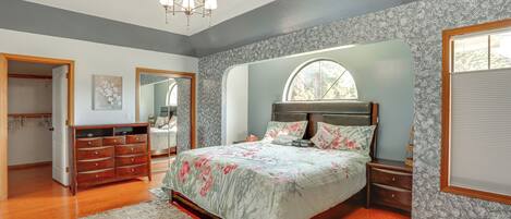 A bedroom with a bed, dresser, nightstands, and a walk-in closet.