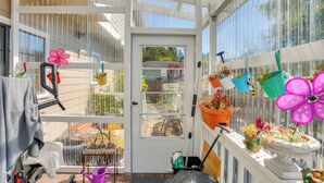 A sunroom with a door, potted plants, a small table, and a chair. - 3 Mi to Sequoia Park Zoo: Spacious Home w/ Sunroom (Eureka)