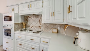 A kitchen with white cabinets, a stove, and a coffee maker. - 5 Mi to UT Dallas: Family-friendly Duplex w/ Patio (Richardson)
