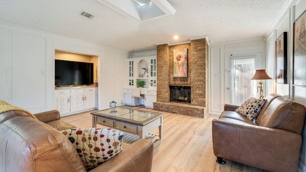 A living room with a fireplace, leather sofas, a glass coffee table, and a TV. - 5 Mi to UT Dallas: Family-friendly Duplex w/ Patio (Richardson)
