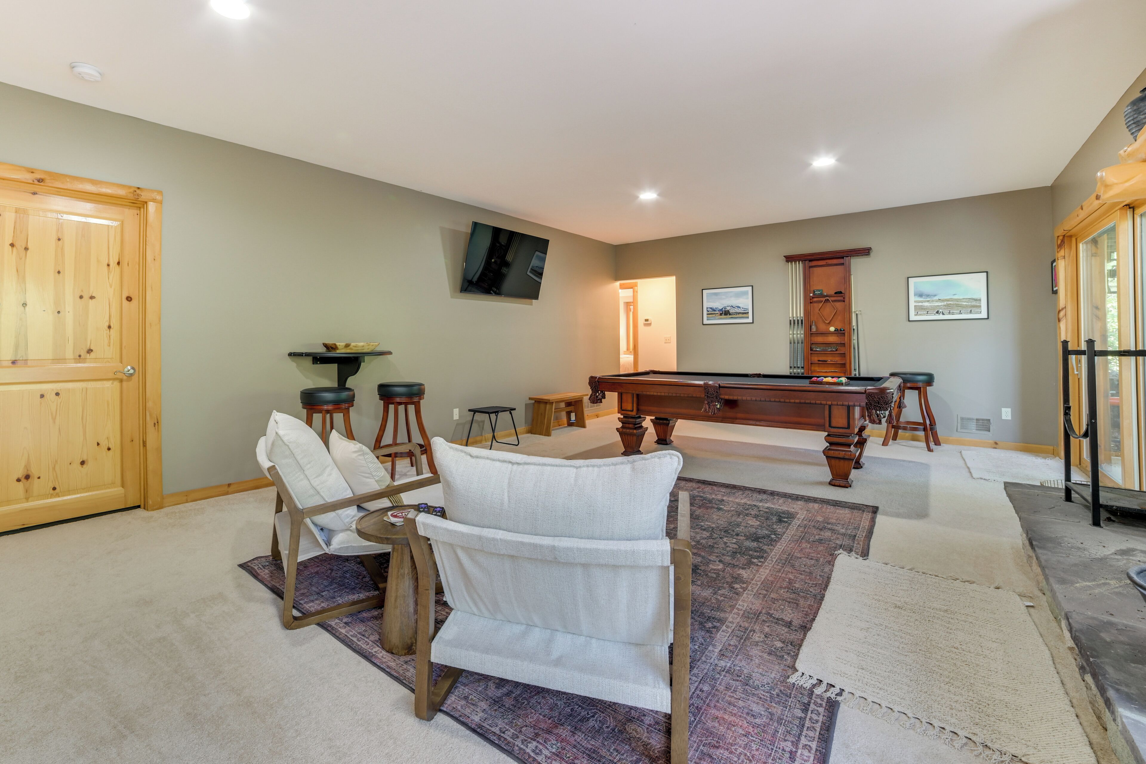 A home interior with a pool table, chairs, and a billiards rack.