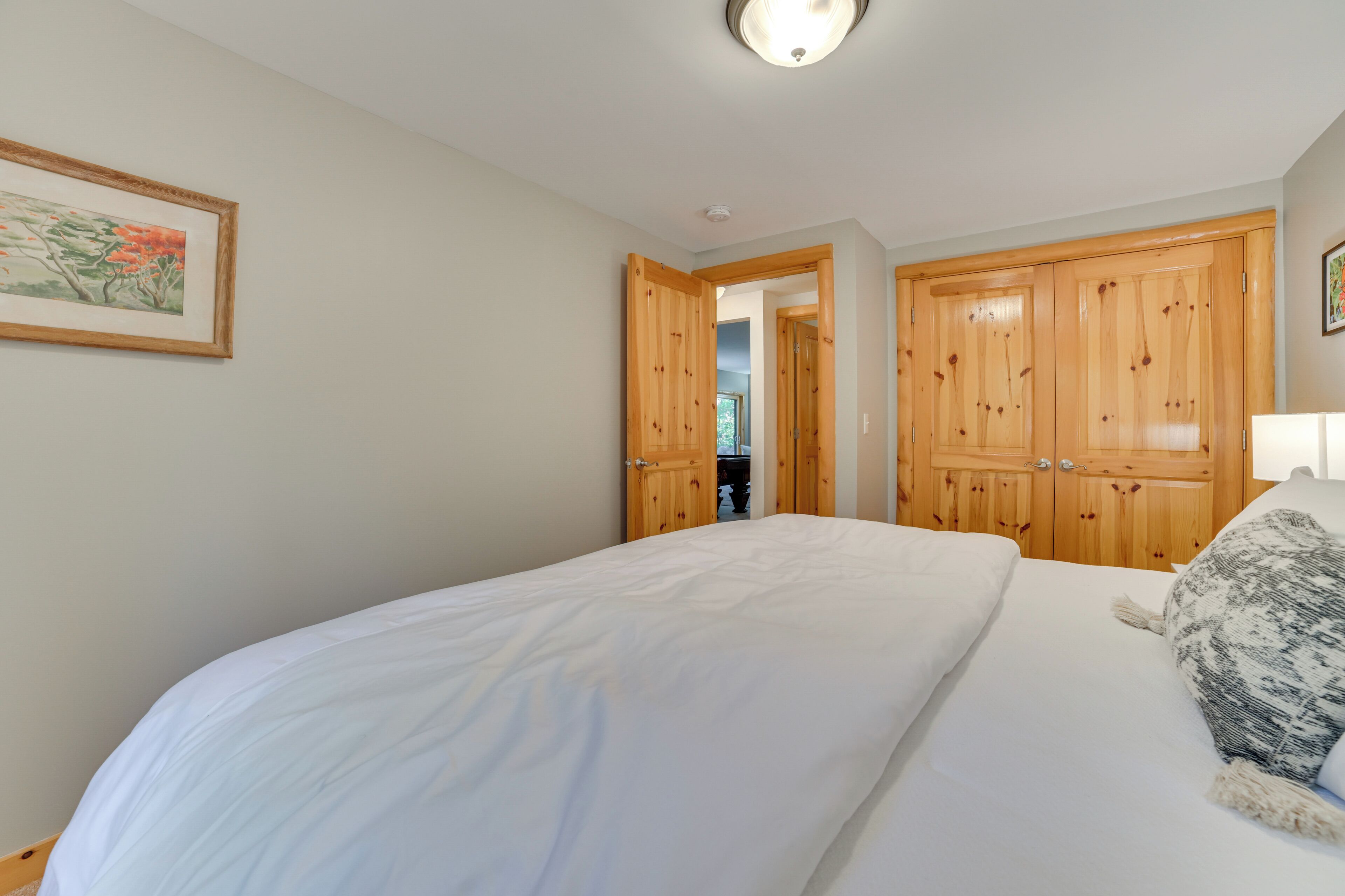 Un dormitorio con una cama grande, un armario de madera y un cuadro enmarcado en la pared.
