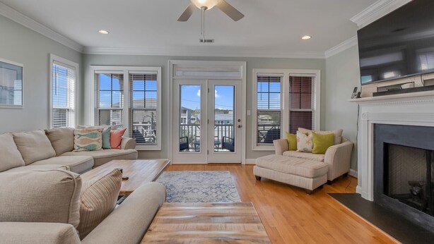 A spacious living room with a fireplace, a ceiling fan, and large windows with blinds. - Stay Kureous - Just 3 blocks from the beach with Rooftop Views & Multiple Outdoo (Kure Beach)