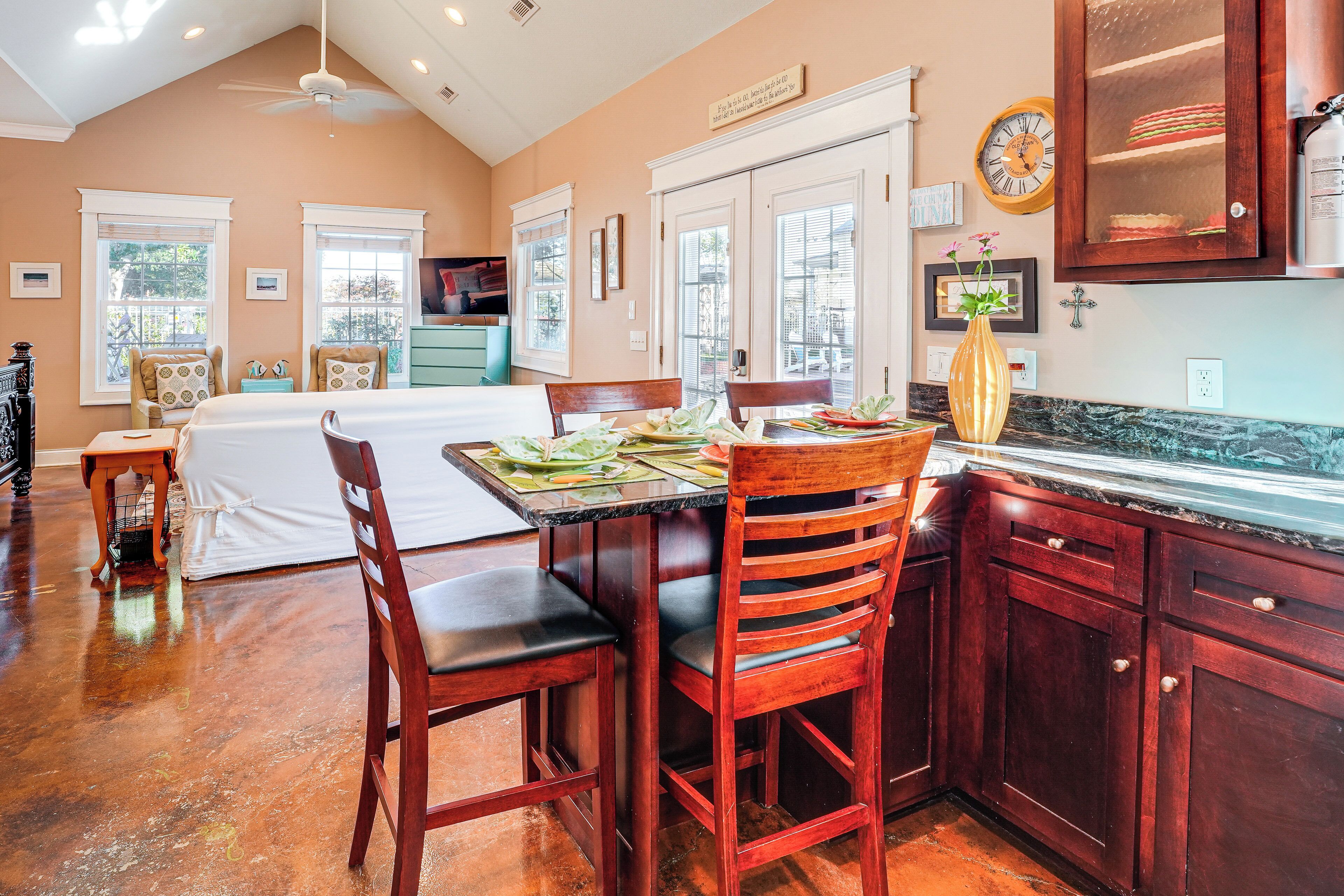 A kitchen with wooden cabinets, a dining table with chairs, and a large window with blinds.
