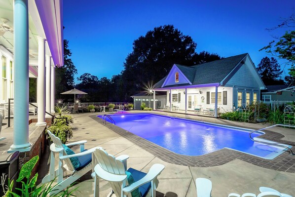A swimming pool with lounge chairs, a covered patio, and a building with a gabled roof. - Heart of Historic Chickamauga! Chic Studio w/ Pool (Chickamauga)