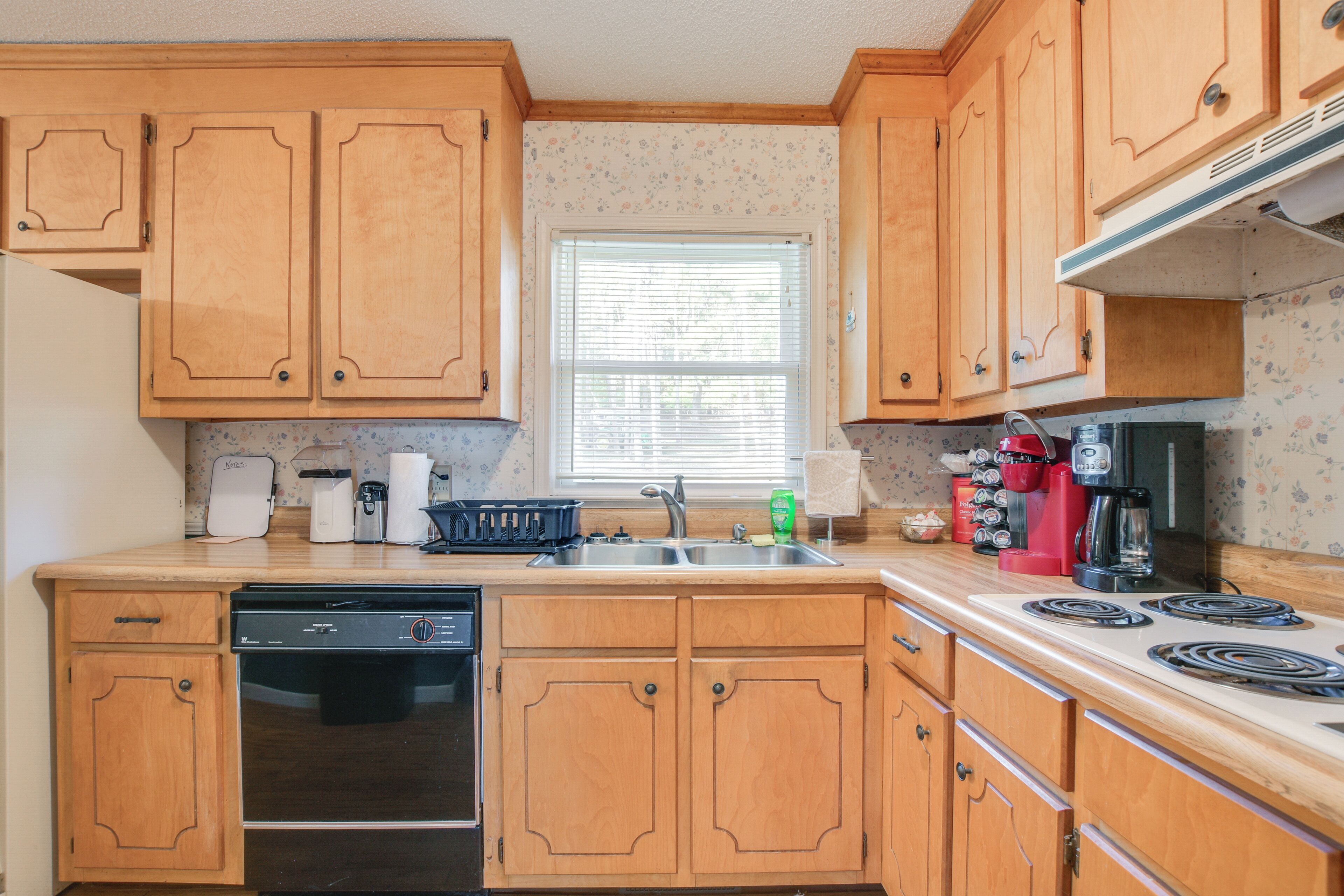 A kitchen with wooden cabinets, a dishwasher, a stove, and various appliances.