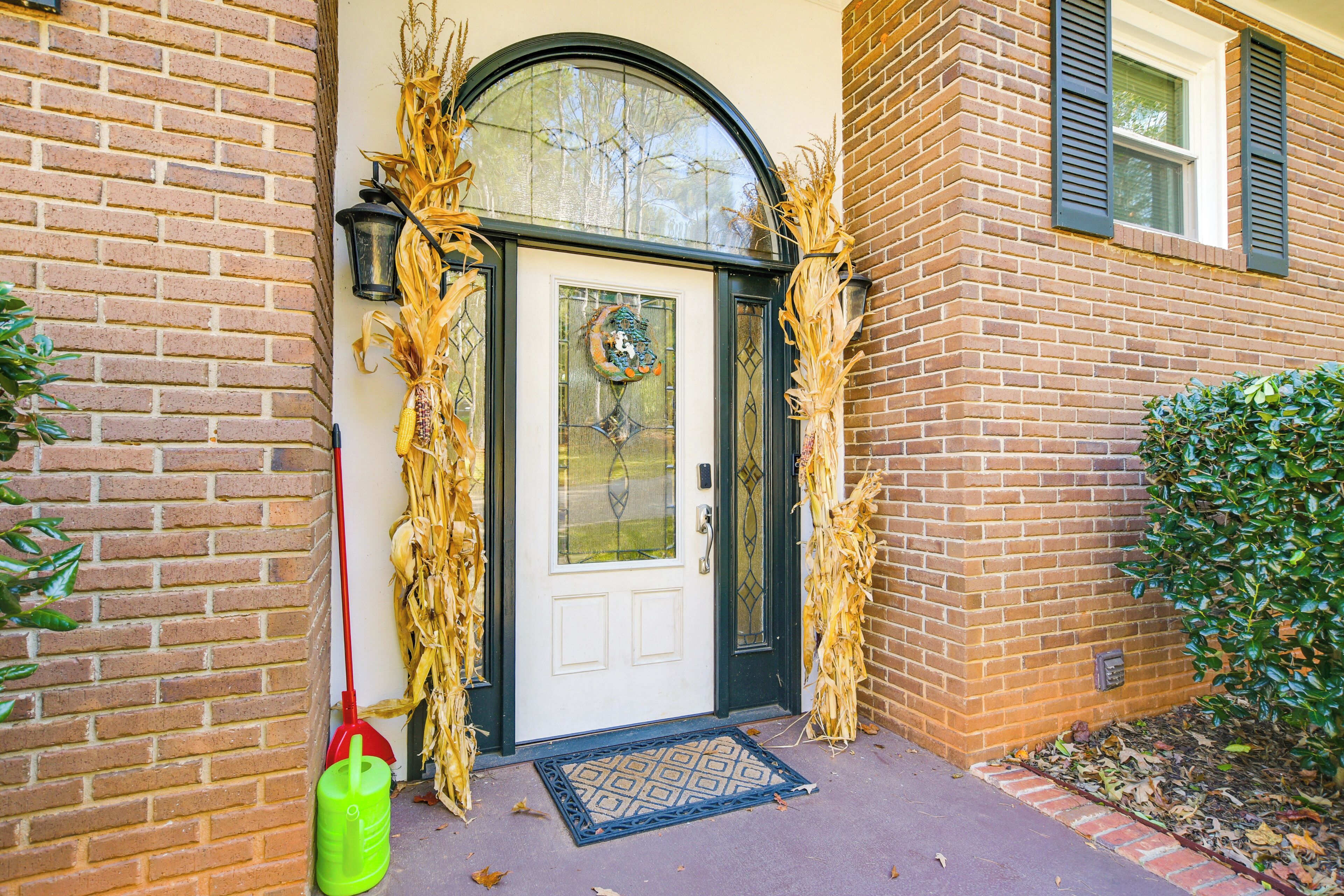 A brick house with a white door, a doormat, and a wreath.