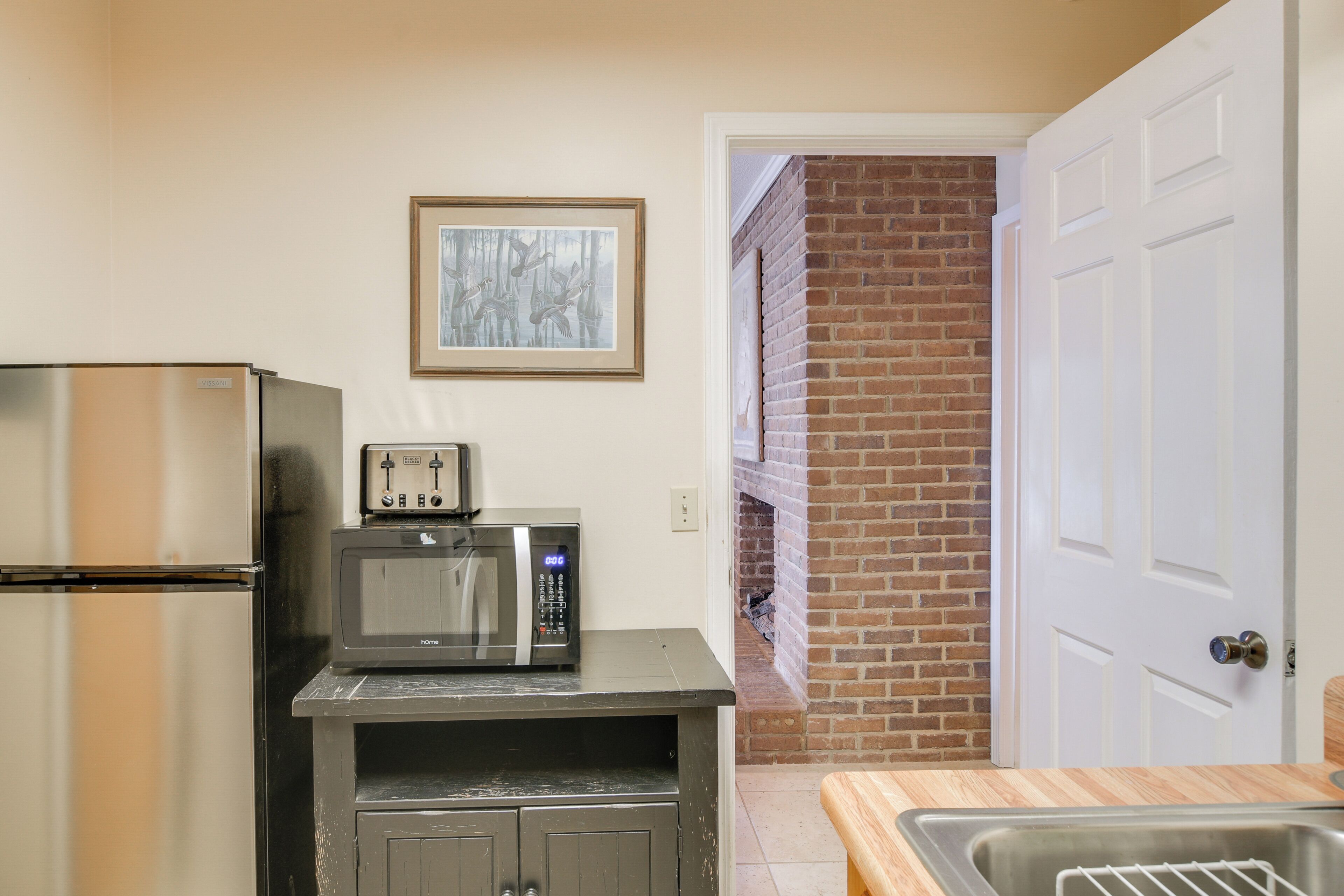 Una cocina compacta con refrigerador, microondas y lavamanos.