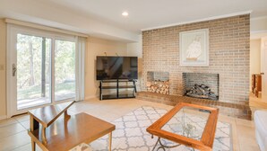 A spacious living room with a brick fireplace, a television, and a dining area.