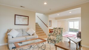 A living room with a sofa, armchair, coffee table, and a staircase.