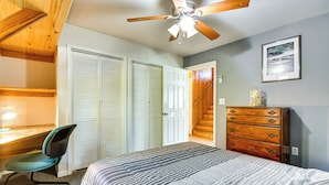 A bedroom with a bed, a desk with a chair, a dresser, and a ceiling fan.
