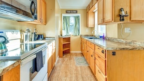 A kitchen with wooden cabinets, a stainless steel range hood, a microwave, and a 'Farm to Fork' sign.