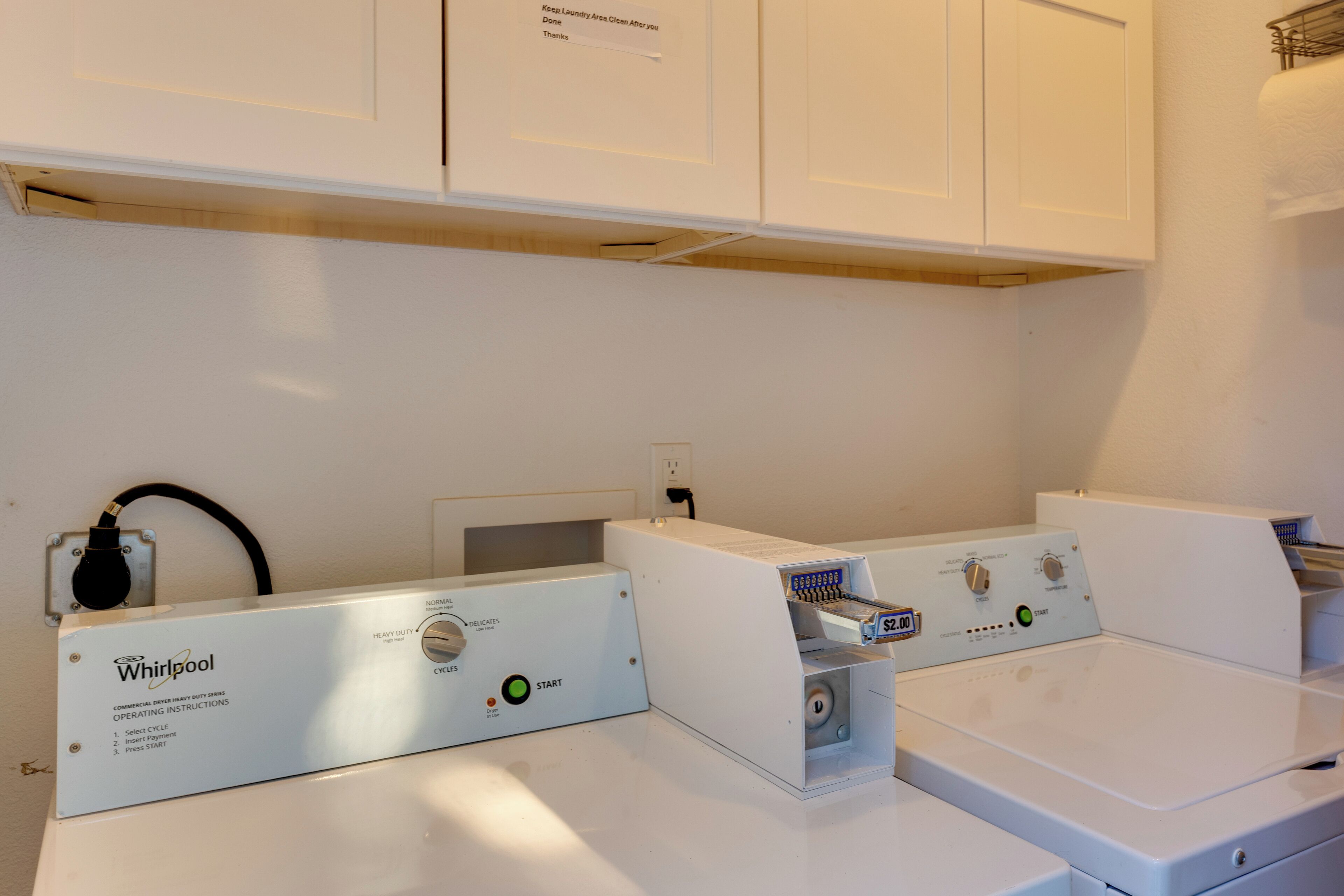 A commercial dryer with operating instructions and a payment slot.