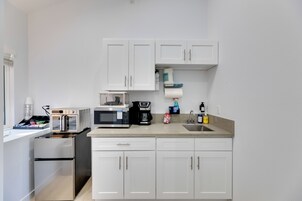 A compact kitchen with white cabinets, a microwave, a toaster, and a small refrigerator.